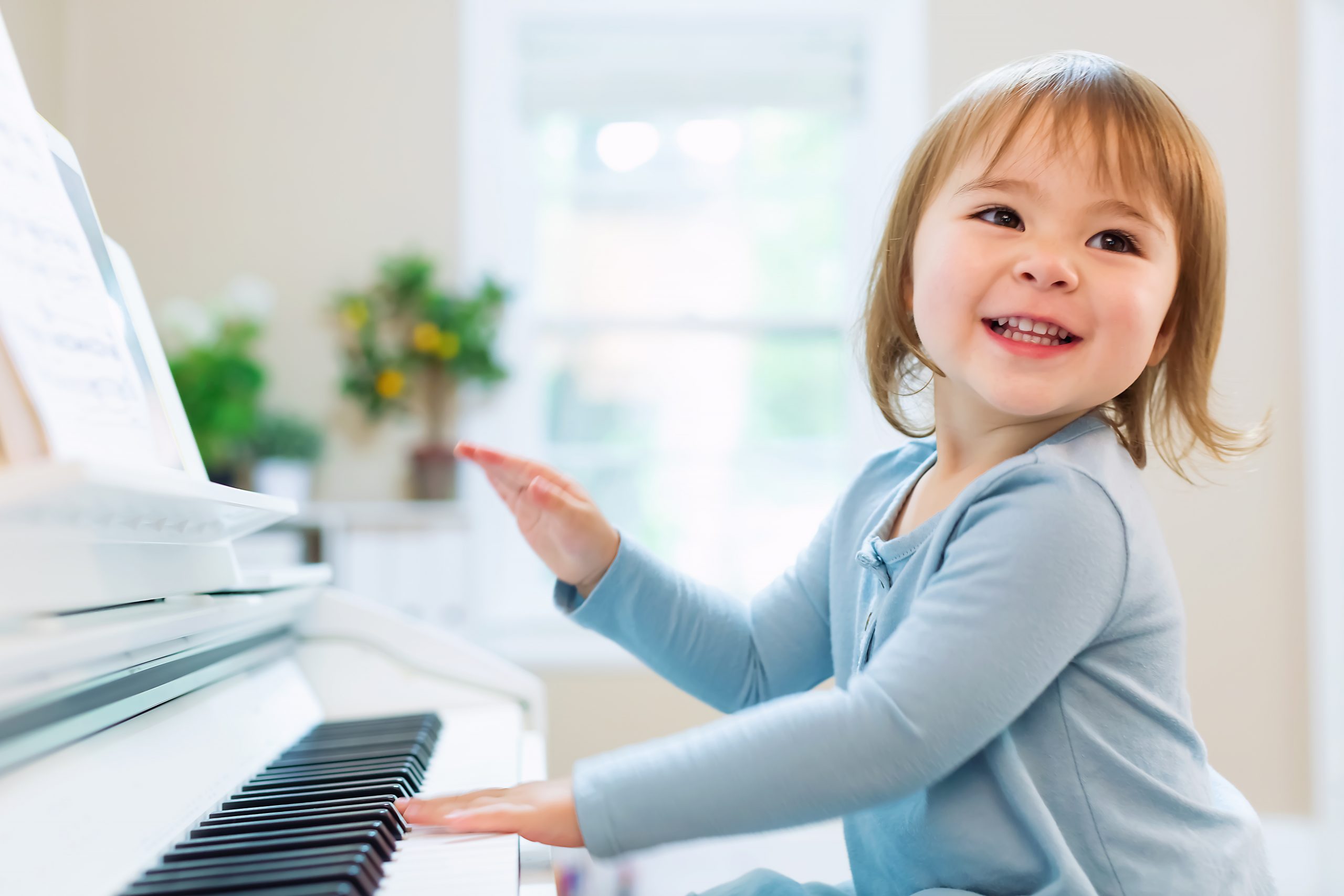 Happy smiling toddler girl excited to play the piano
