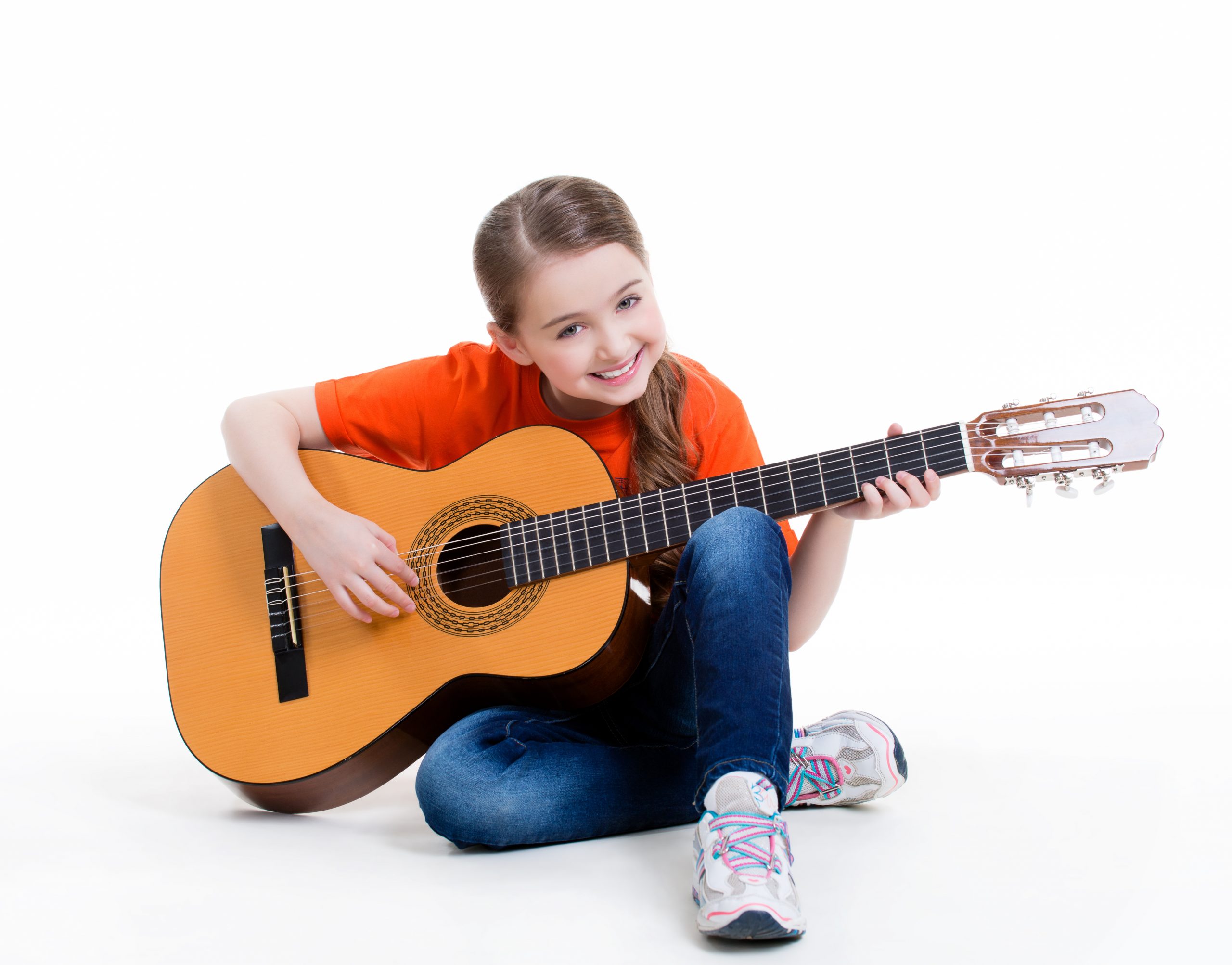 Cute girl plays on the acoustic guitar with bright emotions -  isolated on white background.